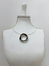 modern silver tone necklace with a round pendant in sleek dark brown and silver, finished with
delicate cut out details displayd on a mannequin