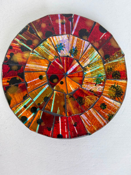 Round mosaic coaster with a colourful pattern on a white background