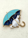 brooch with a cat under an umbrella on a textured white background