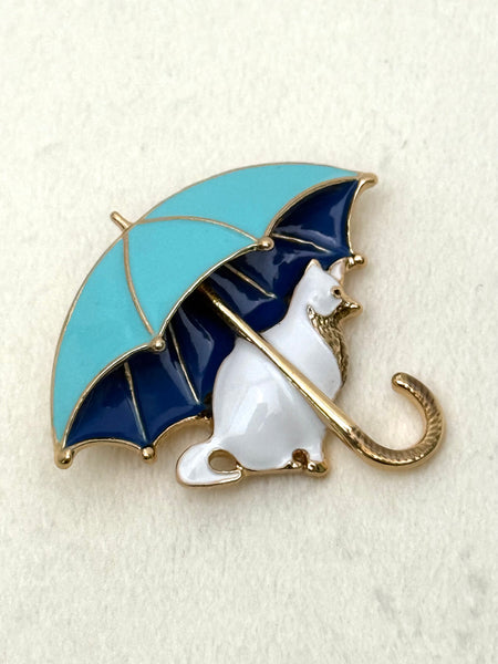 brooch with a cat under an umbrella on a textured white background