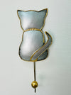 A handmade silver cat-shaped hook with gold detailing, mounted on a wall.