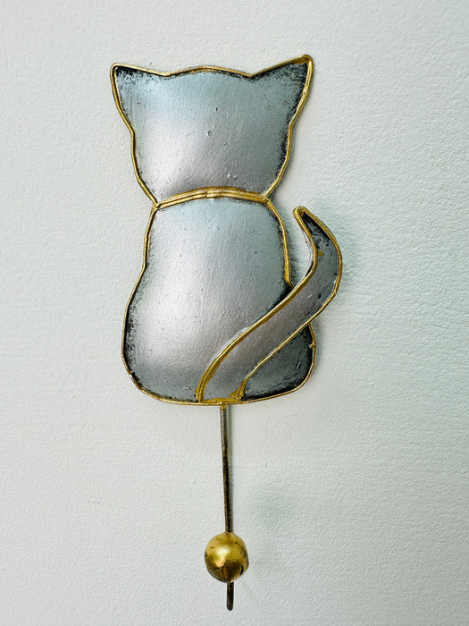 A handmade silver cat-shaped hook with gold detailing, mounted on a wall.