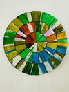 A hand painted glass round mosaic coaster with a citrus color palette, made of glass tiles on a MDF backing.