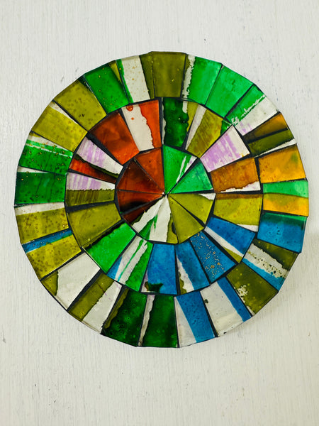 A hand painted glass round mosaic coaster with a citrus color palette, made of glass tiles on a MDF backing.