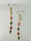 A pair of colorful floral dangle earrings with gold-colored metal and multicolored gemstone-like accents, displayed against a neutral background.