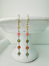 Colorful flower-shaped earrings on a white stand