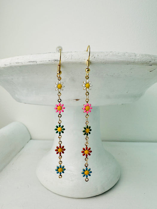 Colorful flower-shaped earrings on a white stand