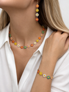 Colorful floral necklace and earrings on a model wearing a white shirt.