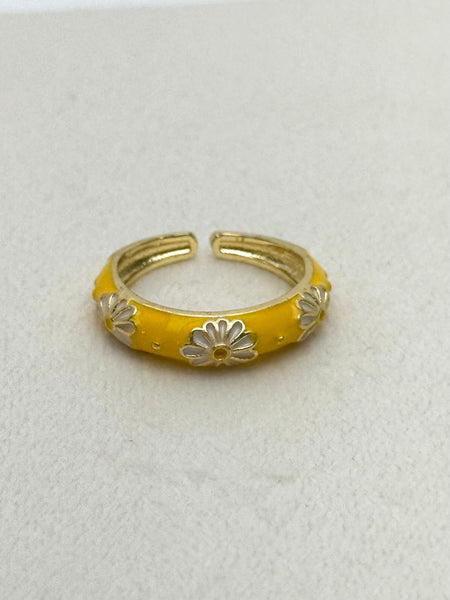 Yellow ring with silver floral designs on a light gray background