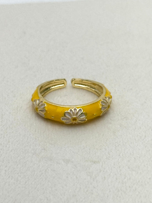 Yellow ring with silver floral designs on a light gray background