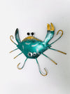 Angled view of green metal crab wall art showing painted texture and raised legs