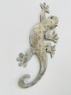 Side view of small white and gold metal gecko wall art highlighting textured finish