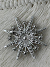back view of silver star-shaped brooch on a textured fabric background
