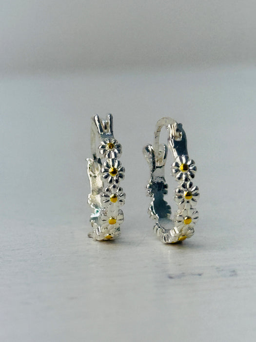 Silver hoop earrings with floral designs on a light gray background