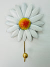 Handmade metal daisy flower hook with white petals and gold detailing on white background.