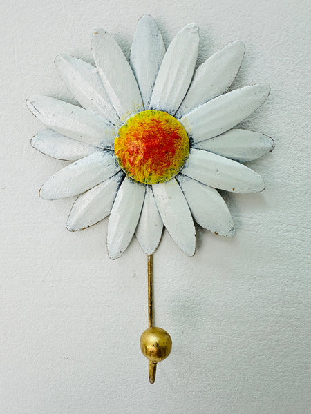 Handmade metal daisy flower hook with white petals and gold detailing on white background.