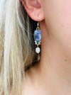 A delicate pair of dangle earrings with purple teardrop-shaped stones and pearl drops.
