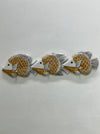 Three decorative fish wall hooks arranged in a row on a textured white wall. The fish have a warm tan and white scale pattern with black and gray fins.