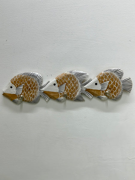 Three decorative fish wall hooks arranged in a row on a textured white wall. The fish have a warm tan and white scale pattern with black and gray fins.