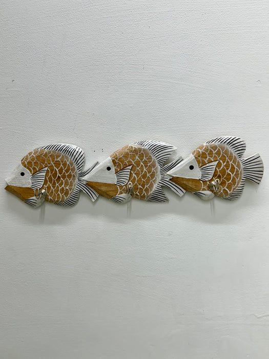 Three decorative fish wall hooks arranged in a row on a textured white wall. The fish have a warm tan and white scale pattern with black and gray fins.
