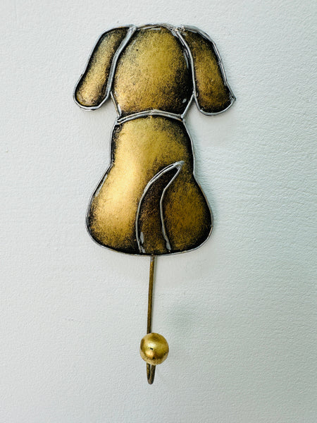A hand painted gold dog hook with silver detailing mounted on a wall.