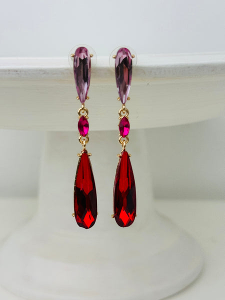 Elegant 7 cm long drop earrings with amethyst-purple, ruby-red and deep-red crystals in gold-tone finish, displayed on a white background.