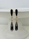 Elegant 7 cm long drop earrings with black stones, clear crystal and smoky teardrop in gold-tone finish, displayed on a white background.