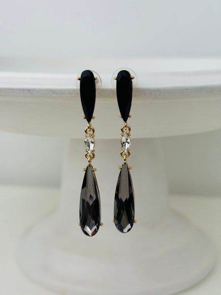 Elegant 7 cm long drop earrings with black stones, clear crystal and smoky teardrop in gold-tone finish, displayed on a white background.