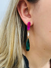 Elegant 7 cm long drop earrings with purple, clear crystal and emerald green teardrop in gold-tone finish, dispalyed on a model.
