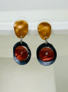 Drop earrings with layered circular enamel shapes in bronze, copper and navy on silver tone setting, worn on a model, displayed on white background