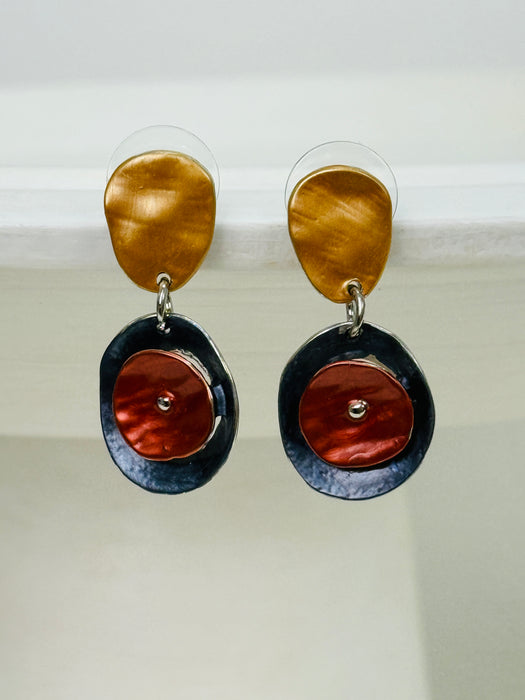 Drop earrings with layered circular enamel shapes in bronze, copper and navy on silver tone setting, worn on a model, displayed on white background