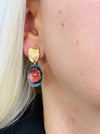 Drop earrings with layered circular enamel shapes in bronze, copper and navy on silver tone setting, worn on a model