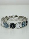 Elastic Aurea bracelet with white and grey enamel circular design.