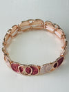 Elastic Aurea bracelet with rose-gold enamel circular design in gold-tone finish.