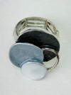 Silver-tone elastic ring with three layered enamel discs in dark and light grey.