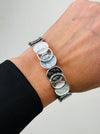 White and grey silver plated bracelet with circular links on a wrist.