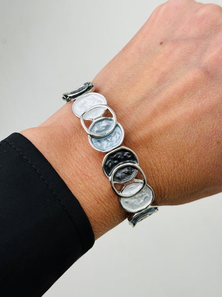 White and grey silver plated bracelet with circular links on a wrist.