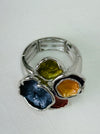 Silver-tone elastic ring with coloured  lily pad detailing, displayed on a table. 
