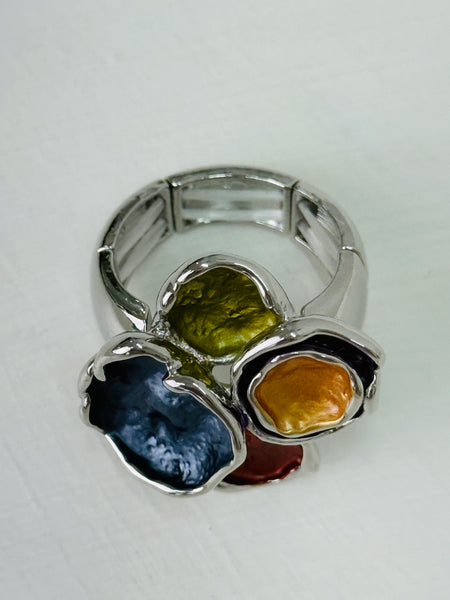 Silver-tone elastic ring with coloured  lily pad detailing, displayed on a table. 