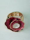 Gold ring with a rose-gold flower-shaped design on flatlay.