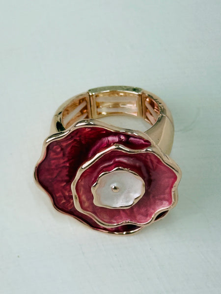 Gold ring with a rose-gold flower-shaped design on flatlay.