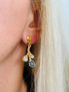 Gold-tone branch drop stud earrings with blue enamel teardrops and clear glass crystals on model.