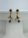 Gold-tone branch drop stud earrings with blue enamel teardrops and clear glass crystals on white background.