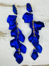 12 cm long statement drop earrings with cascading matte royal blue acrylic petals and gold-tone metal accents, displayed on a table.