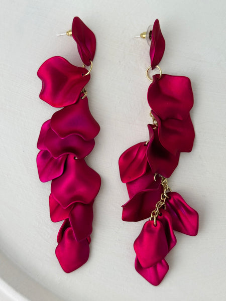 12 cm long statement drop earrings with cascading matte fuchsia acrylic petals and gold-tone metal accents, displayed on a table.