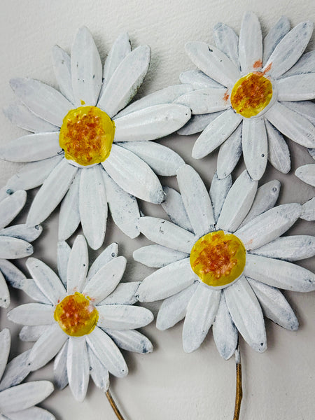 Close-up of metal daisies showing hand-painted petals and yellow centres