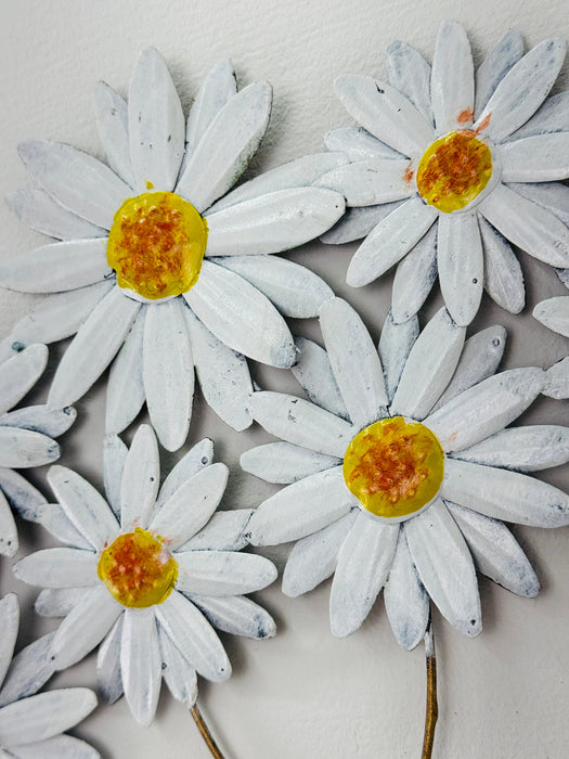 Close-up of metal daisies showing hand-painted petals and yellow centres