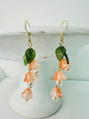 Delicate bell flower drop earrings with soft peach petals and green leaf details.