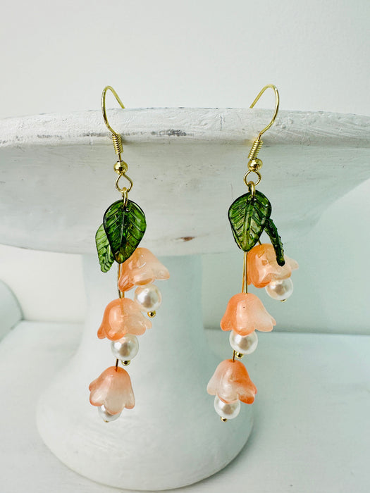 Delicate bell flower drop earrings with soft peach petals and green leaf details.