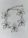 Delicate silver-tone floral bracelet with linked open-petal flower design and adustable chain extender, displayed on a white background.